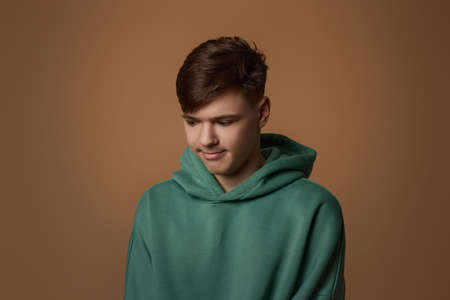 upset young guy in sweatshirt isolated on brown background.の写真素材
