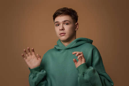 young scared man in sweatshirt on brown background.の写真素材