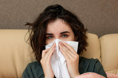 sick girl having influenza symptoms coughing at homeの写真素材