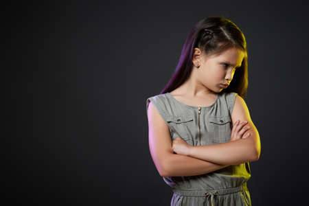 unsatisfied little child girl on dark background.の写真素材
