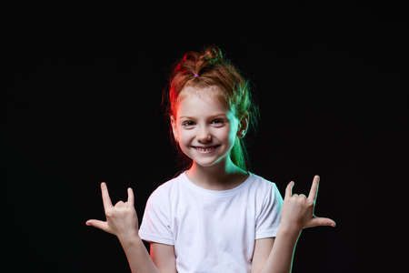 child girl with crazy expression doing rock symbol with hands up