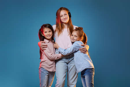 three kids girls standing together on blue backgroundの写真素材