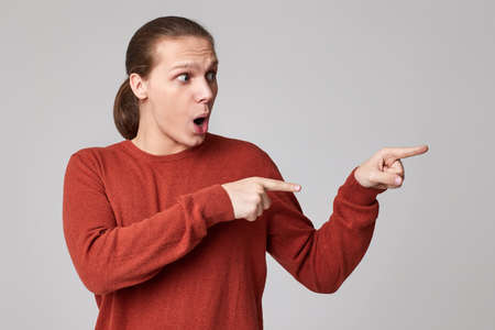 young man pointing finger away at empty space