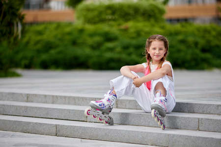 cute little girl on roller skates at park.の写真素材