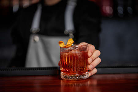 Barman holding out glass with alcoholic cocktailの写真素材