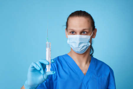 young man wearing doctor uniform holding syringeの写真素材