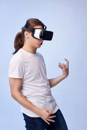 Young man in virtual reality headset plays an imaginary guitar