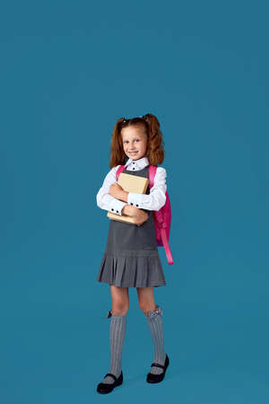 cute schoolgirl with backpack and book full length.