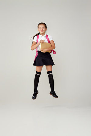 cute happy schoolgirl jumping up with backpack