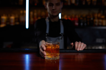 Barman holding out glass with alcoholic cocktailの写真素材
