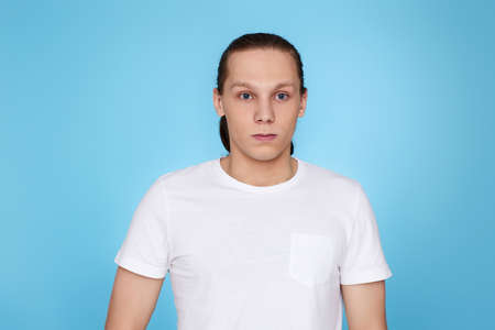young man frowning isolated on blue background.の写真素材