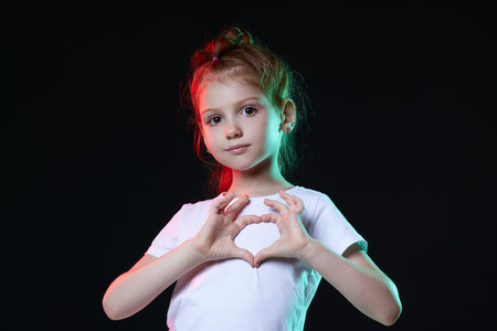 child girl showing love gesture on dark background.の写真素材