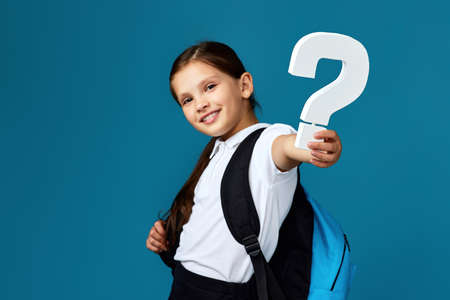 schoolgirl with backpack is holding alarm clockの写真素材