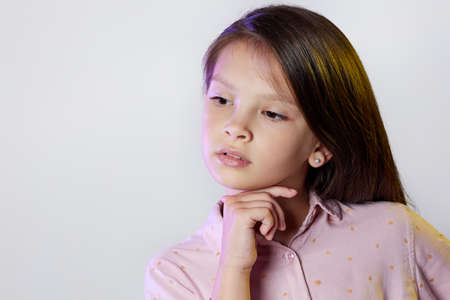 thoughtful little child girl on white background.の写真素材