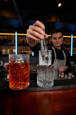 Barman puts the ice cubes into a glassの写真素材