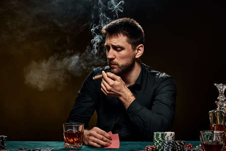 Bearded casino player man playing poker on green tableの写真素材