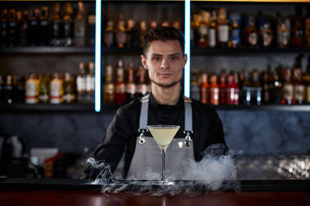alcoholic cocktail with smoke on the bar tableの写真素材