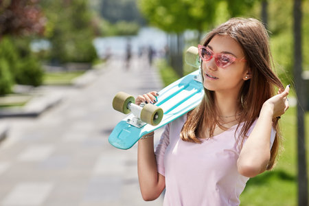 young skateboarder girl with skateboard standing outdoorsの写真素材