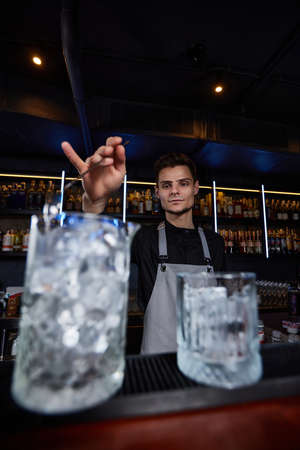 Barman stirring ice cubes in cocktail glass with spoonの写真素材