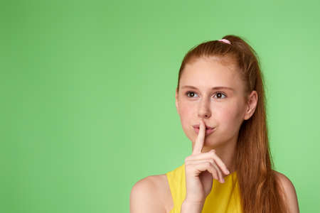 teen girl showing shhh taboo sign with finger to lipsの写真素材