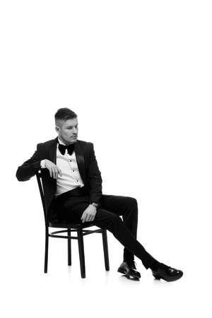 handsome man in tuxedo sitting on chairの写真素材