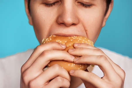 Very hungry young man holding tasty hamburgerの写真素材