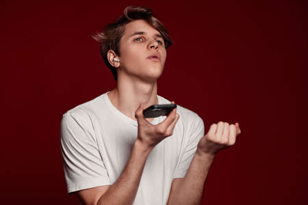 man with earphones man recording audio message on mobile phoneの写真素材