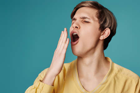 caucasian yawning man on blue backgroundの写真素材