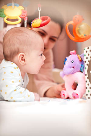 cute newborn baby play with toy with mother