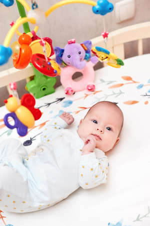 newborn baby in crib with toys at home