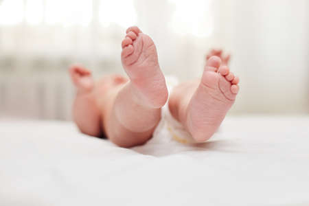 Newborn feet. little baby lying on white bed.