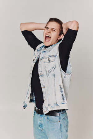young man with mouth opened in shout on gray background