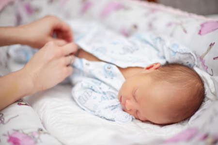 Mother dressing her cute hewborn baby daughter