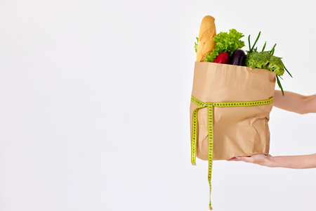 female hand holding eco paper bag with groceriesの写真素材