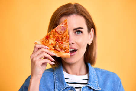 woman covering her eyes with a slice of fresh pizzaの写真素材