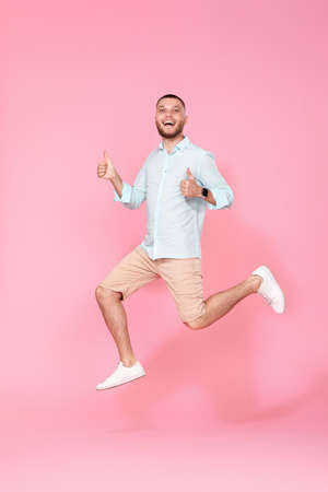 man in summer clothes jumping on pink background.の写真素材