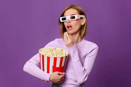 woman watching movie film, holding bucket of popcorn