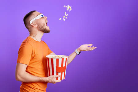 young man in 3d glasses throwing up and eating popcornの写真素材