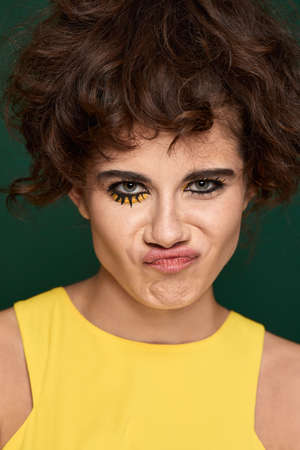 young curly woman with creative make-up in yellow dressの写真素材