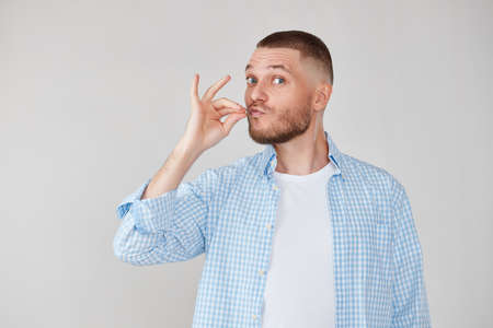 man with pouted lips showing gourmet sign with fingers tastyの写真素材