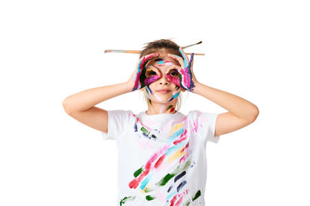 little child girl in colorful paint with paintbrush in hairの写真素材