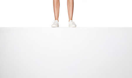 female legs in white sneakers on white banner.の写真素材