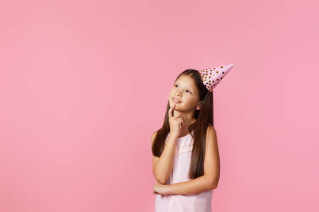happy little girl with party cone making wish on her birthday