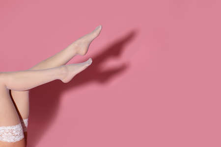 female legs in white stockings on pink background.の写真素材