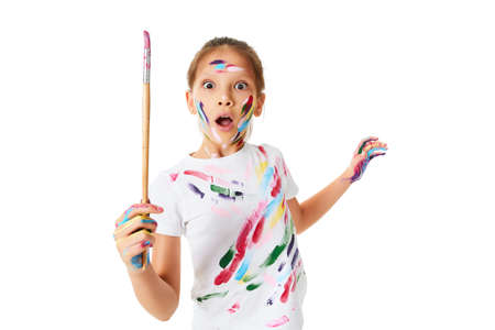 child girl in colorful paint holding brush in one handの写真素材