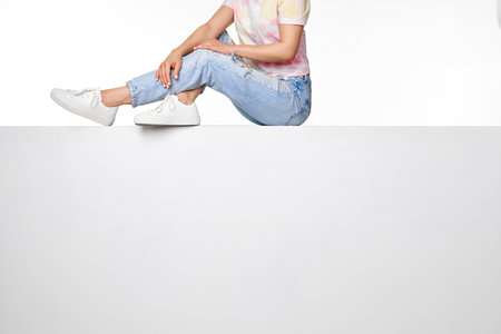 female legs in jeans and white sneakers sitting
