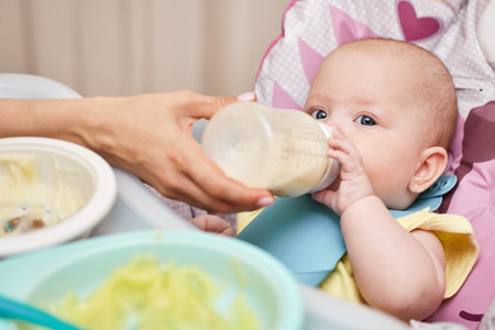 Adorable baby drinks milk from a bottleの写真素材