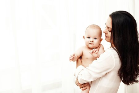 Happy mother holding and hugging adorable newborn babyの写真素材