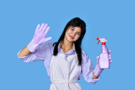 woman in gloves and cleaner apron with sponge and detergent sprayerの写真素材