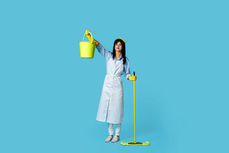 woman in rubber gloves and cleaner apron with cleaning suppliesの写真素材
